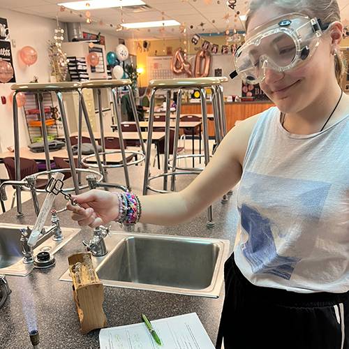 High school student holding beaker over a Bunsen burner